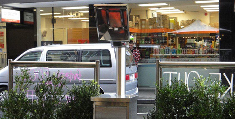 Heatmax outdoor patio heater next to café screens with passing van in background